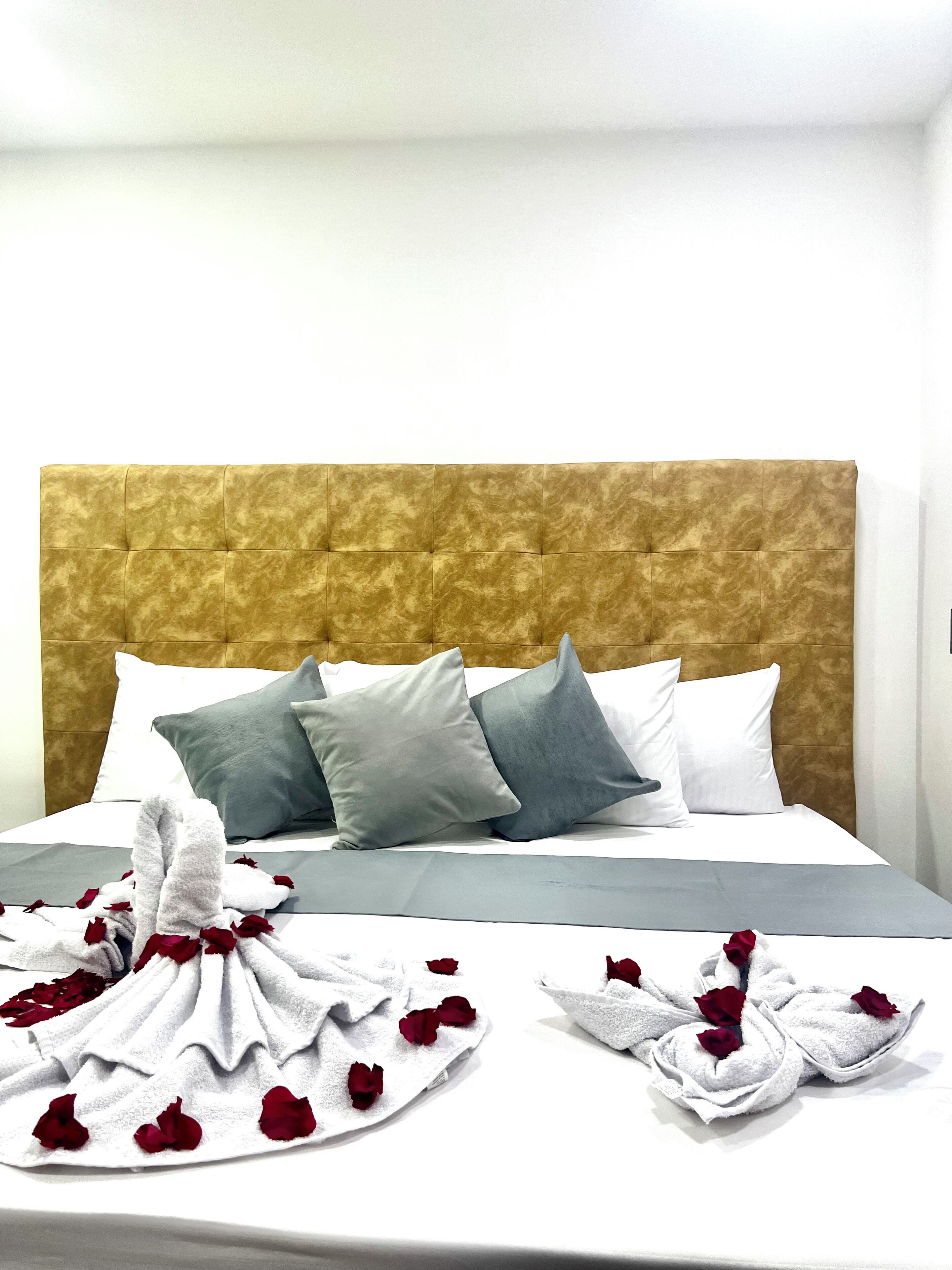 A neatly made bed with a tufted headboard, grey and white pillows, and a white bedspread.