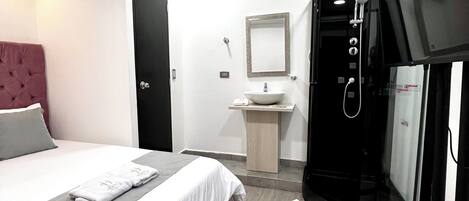 A hotel room with a bed, a small bathroom, and a TV.