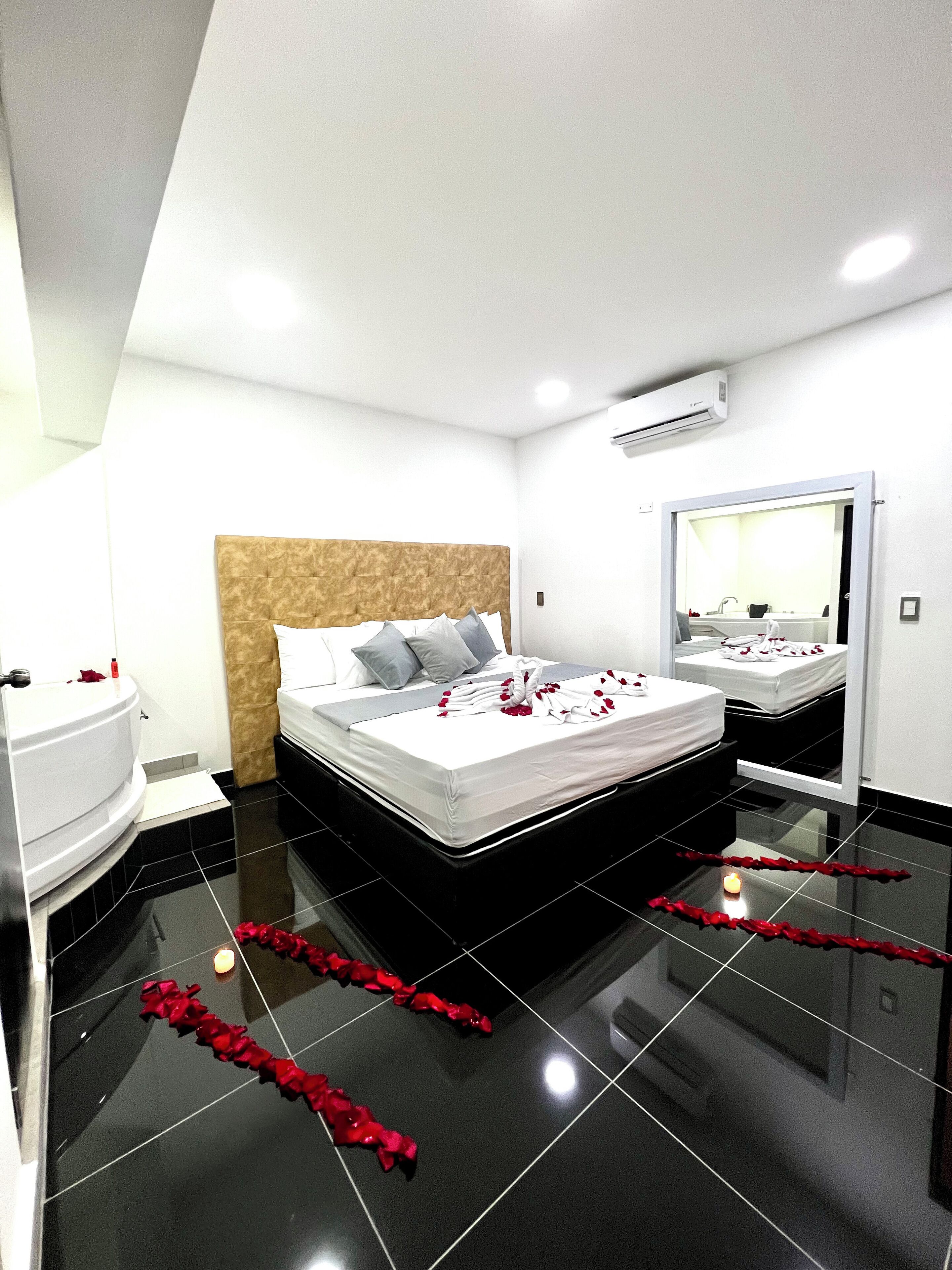 A modern hotel room with a large bed, a bathroom, and a mirror.
