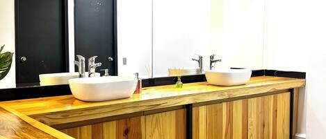 A modern bathroom with two sinks, wooden vanity, and a large mirror.