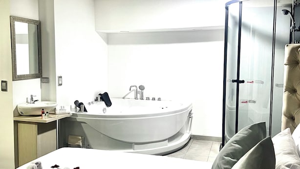 Une chambre d’hôtel moderne dotée d’un grand lit, d’une salle de bain séparée avec baignoire et d’un dressing.
