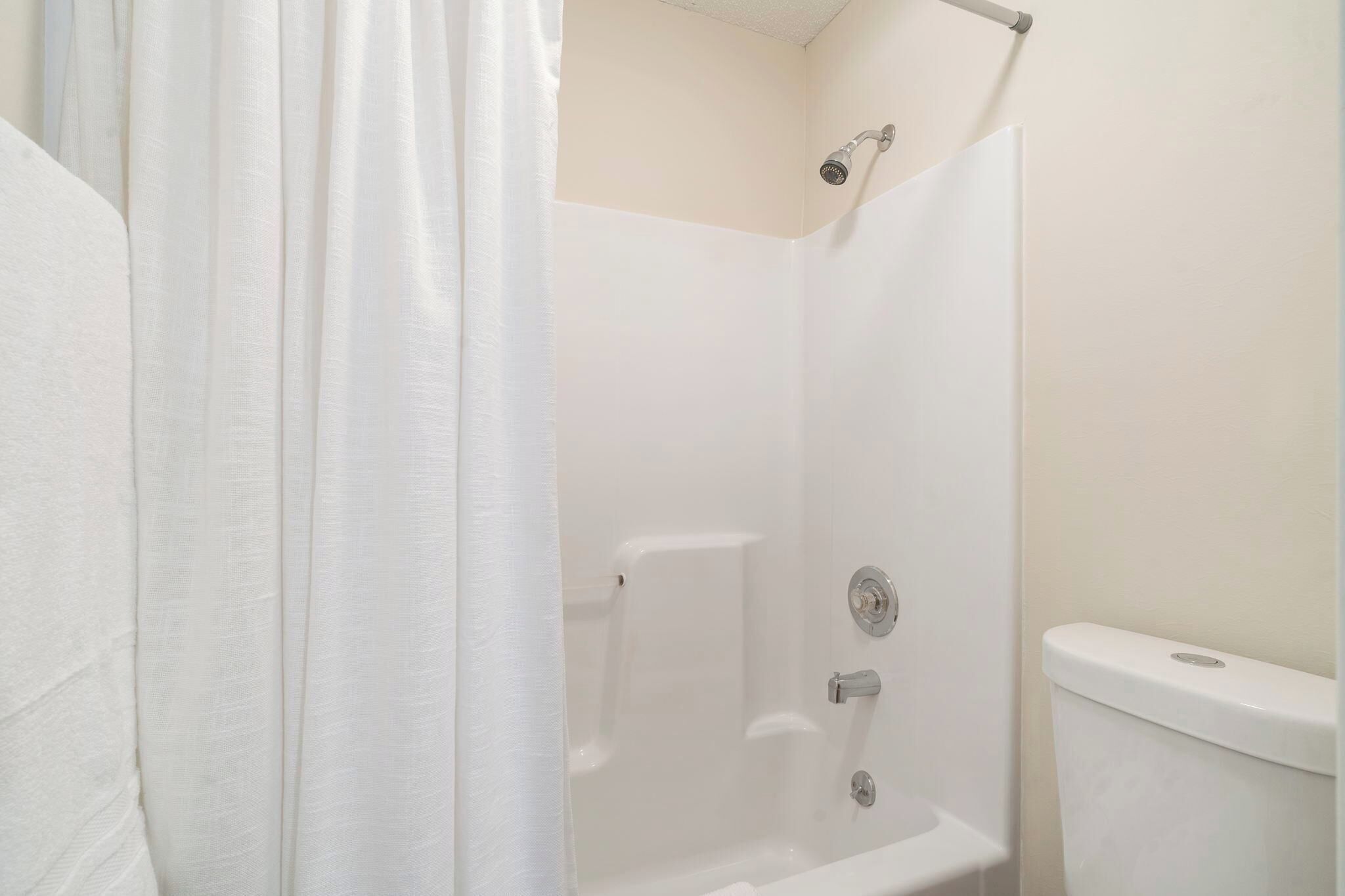 Ein Badezimmer mit Dusche, Toilette und Vorhang.