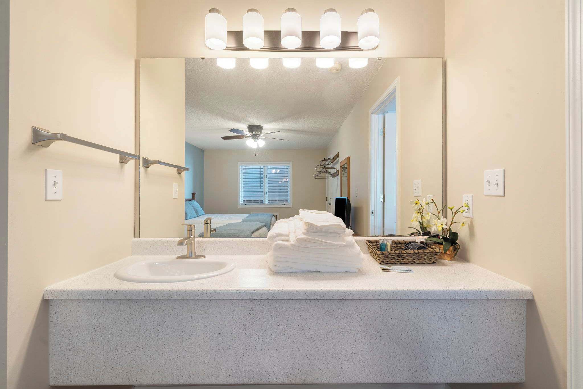 A bathroom with a white sink, a mirror, and a ceiling fan.