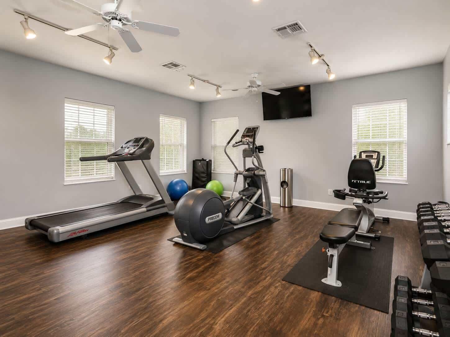 Ein Heimfitnessraum mit Laufband, Crosstrainer, Ergometer und Kurzhanteln.