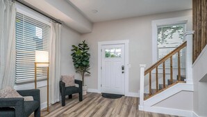 A modern entryway with a wooden staircase, a door with a window, and a potted plant. - Lee Street Lodge (Covington)