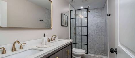 A modern bathroom with a large mirror, dual sinks, and a shower enclosure.