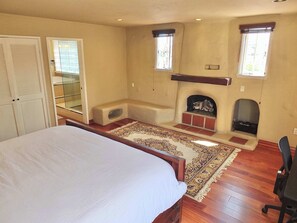 Un dormitorio con cama, chimenea, ventana y espejo.