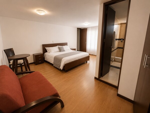 A hotel room with a bed, a desk, a chair, and a wardrobe. - Nogal Suite Hotel Pasto (San Juan de Pasto)