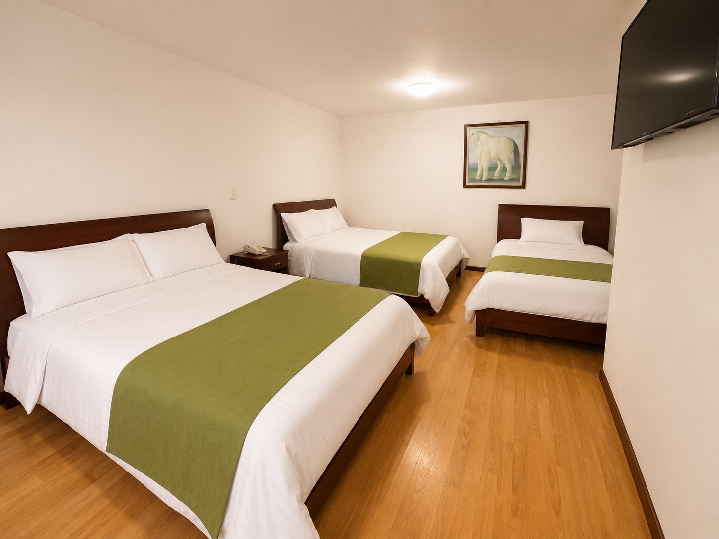 A hotel room with three beds, a flat-screen TV, and a painting of an elephant on the wall.