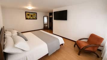 Een hotelkamer met een bed, een stoel, een televisie en een schilderij aan de muur.