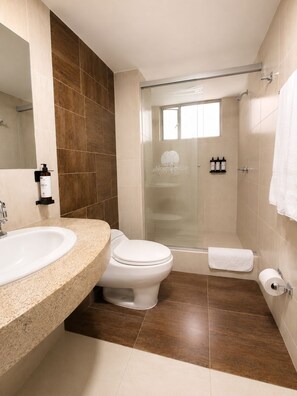 Un baño moderno con ducha, inodoro y lavamanos.