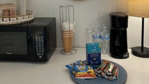 Una kitchenette con microondas, cafetera y un plato de aperitivos.