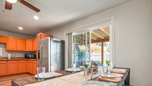 Una cocina moderna con armarios color naranja, un refrigerador de acero inoxidable y un comedor con una mesa de madera para cuatro.
