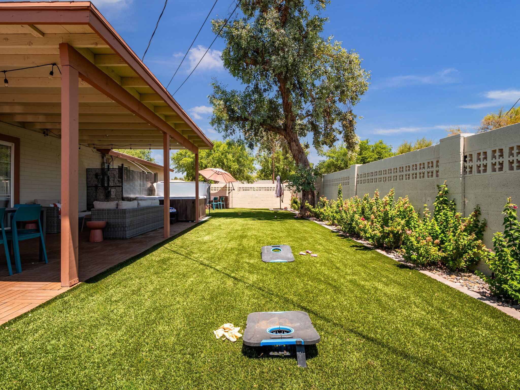 Ein Garten mit überdachter Terrasse, Rasenfläche und Billardtisch.