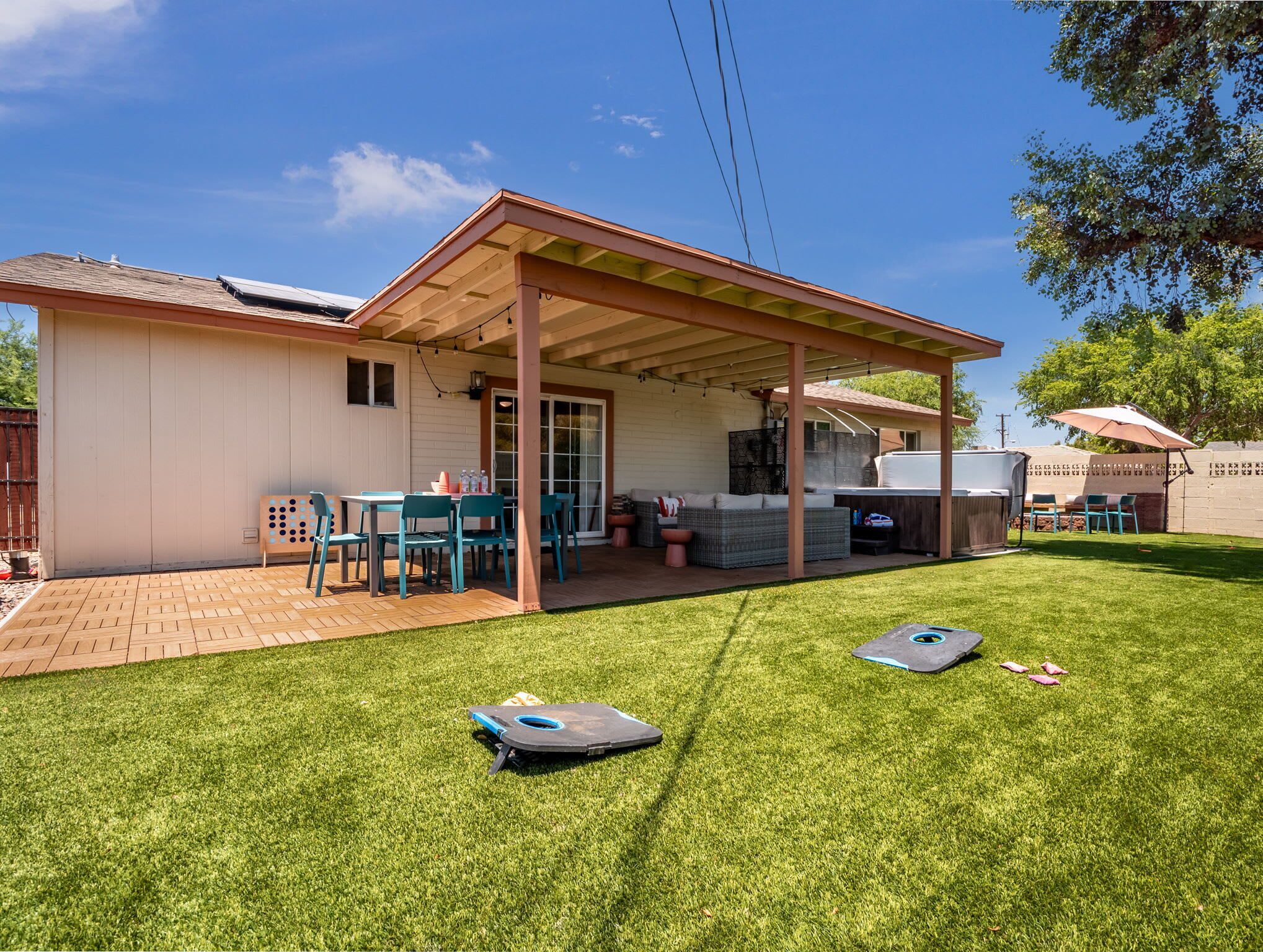 A covered patio area with a barbecue grill, outdoor seating, and a lawn.