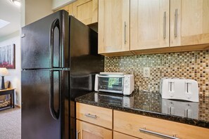 Kitchen features a refrigerator, toaster oven, and wooden cabinets.