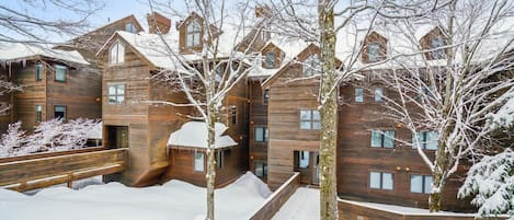 A multi-story wooden building with a snow-covered landscape, wooden railings, and a clear sky.