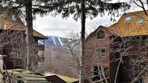 A rustic cabin with a stone foundation, wooden walls, and a sloped roof. - Inviting Two bedroom Two bathroom Highridge Condo B12 (Killington)
