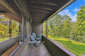 Relax on the porch with a serene view of the lush landscape through large windows.