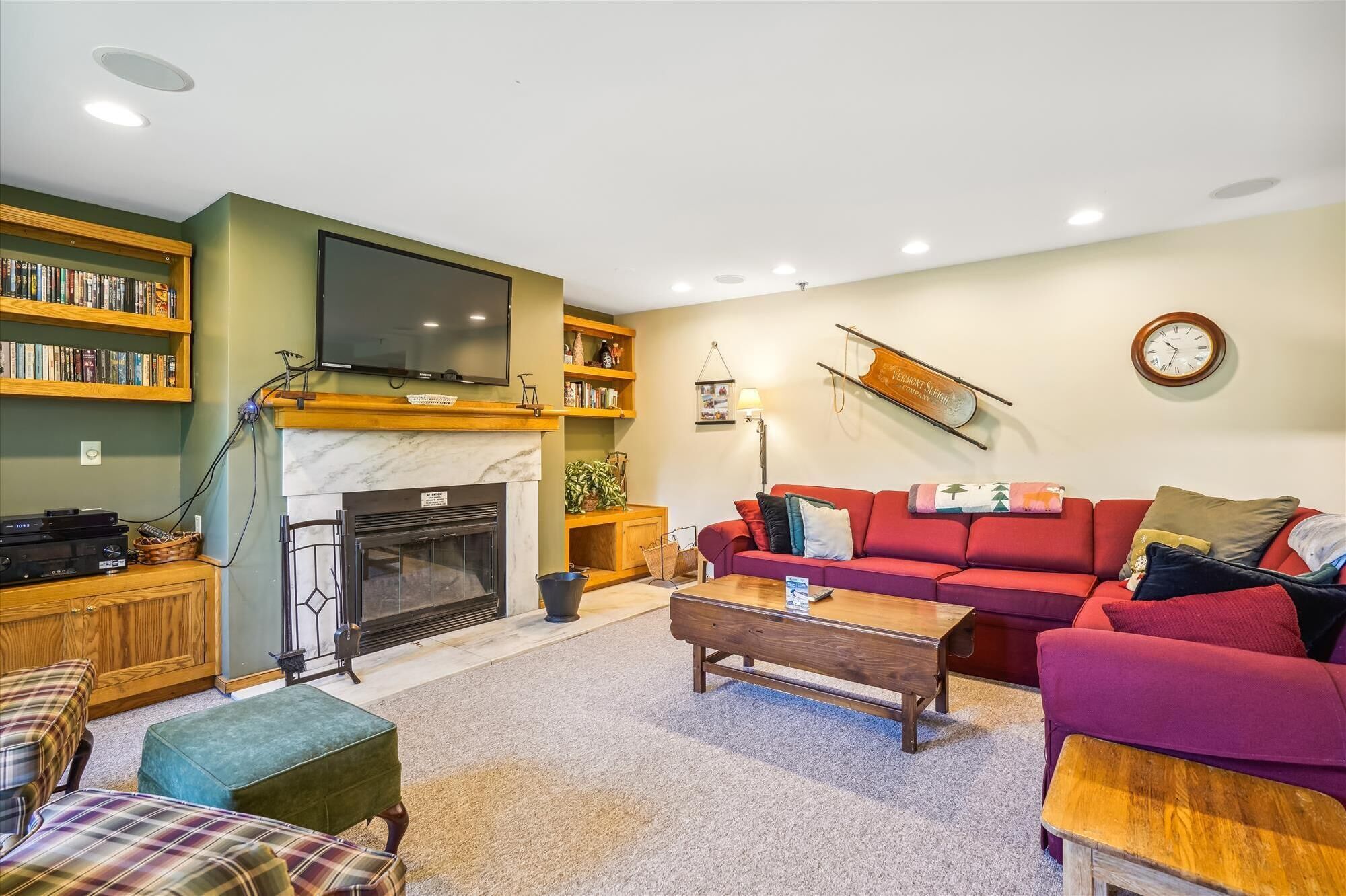 A living room with a fireplace, a television, a red sofa, and a bookshelf.