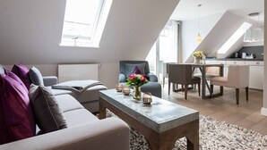 A modern loft apartment with a dining area, a sofa set, and a coffee table with flowers. - Aarnhorst App. 7 - Strandnahe, Moderne 2-zimmer Ferienwohnung auf 76 m² Wohnfläche, für 2 Personen (Wenningstedt-Braderup (Sylt))