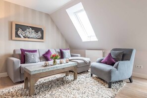 Una sala de estar moderna estilo loft con techo alto, tragaluz, sofá gris, sillón gris, mesa de centro de mármol y un elemento decorativo en la pared.