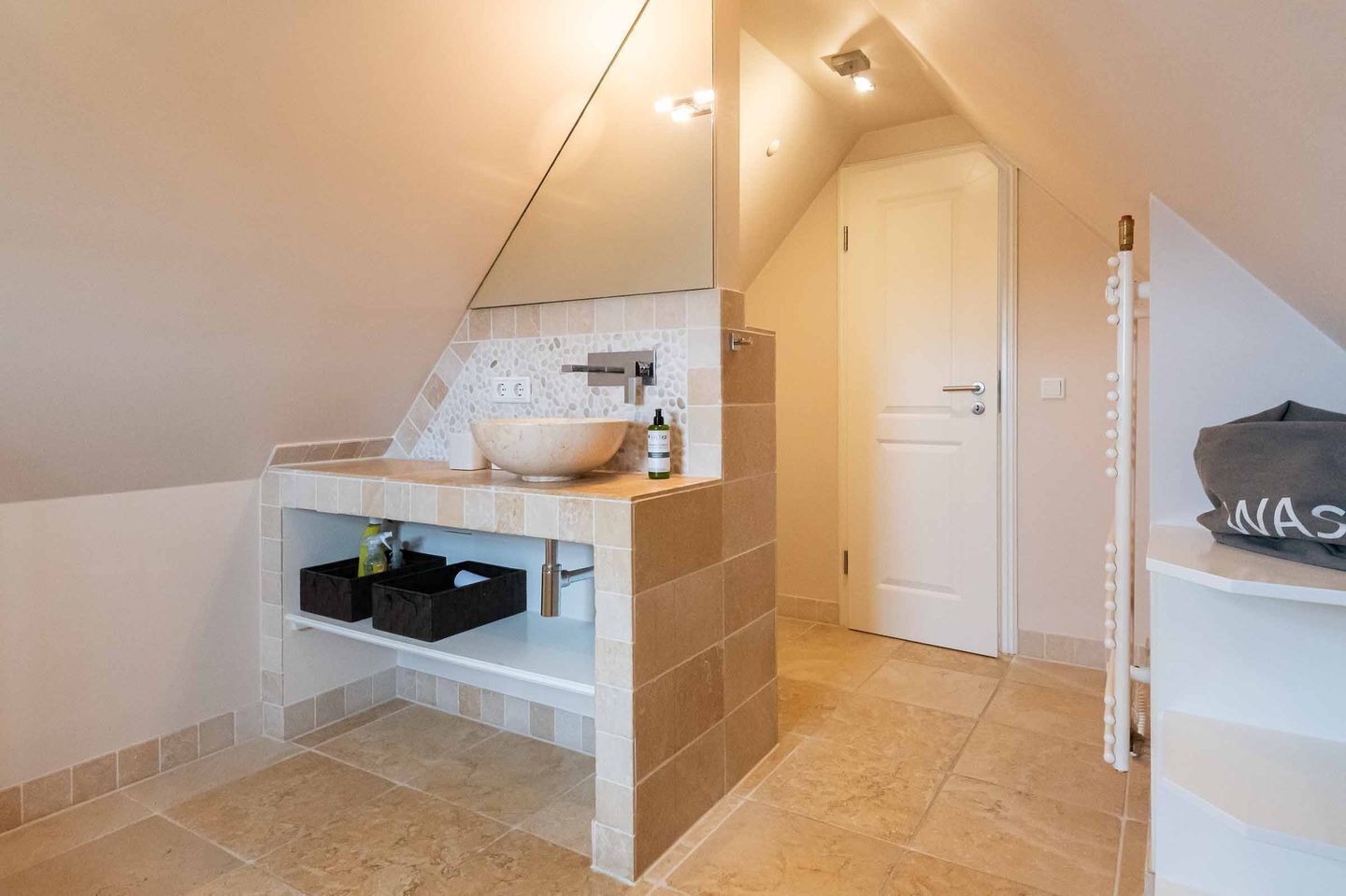 Un baño moderno con un lavabo blanco, un espejo y un perchero para toallas.