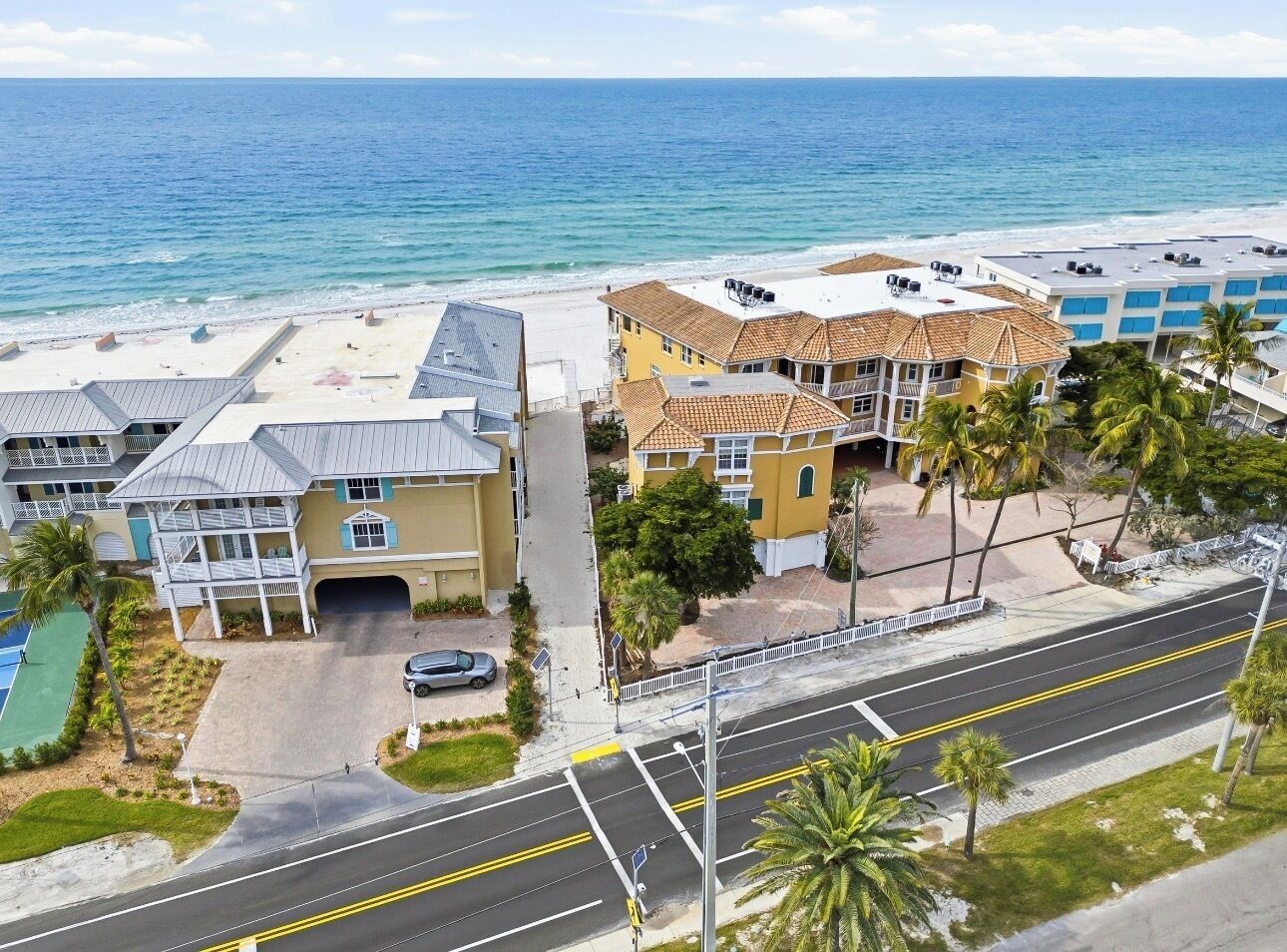 Un hôtel situé sur la côte, avec vue sur la plage, un parking et une route menant à la plage.