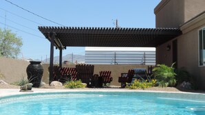 A pool area with a pergola, outdoor seating, and a view of a mountain range. - Sunny Ridge Elegance (Lake Havasu City)