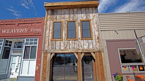 A building with a rustic wooden facade, large windows, and a storefront with a sign.