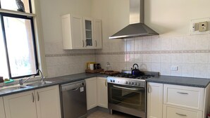Una cucina con mobili bianchi, una lavastoviglie in acciaio inossidabile, un piano cottura a gas e un forno.