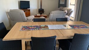 Un soggiorno accogliente con un tavolo in legno, due poltrone, una divano, una televisione e un camino.
