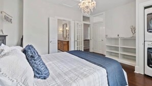 Un dormitorio con una cama grande, una araña, un armario y una lavadora.