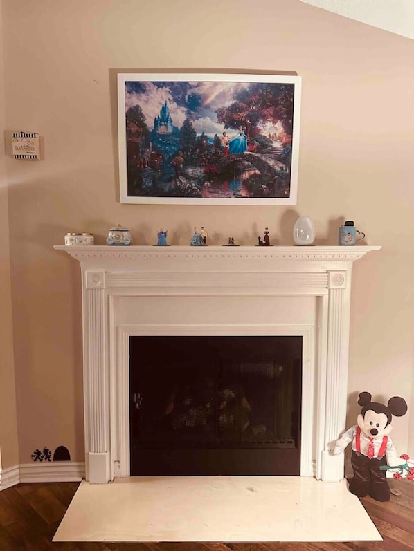 Uma lareira com uma manta decorada com figurines e um quadro emoldurado acima.