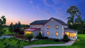 A two-story house with a red roof, multiple windows, and a well-maintained lawn. - Spacious 9BR Family Retreat w/Indoor Heated Pool! (Amsterdam)