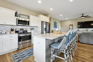 Enjoy cooking in this well-equipped kitchen with a central island, bar stools, and stainless steel appliances.