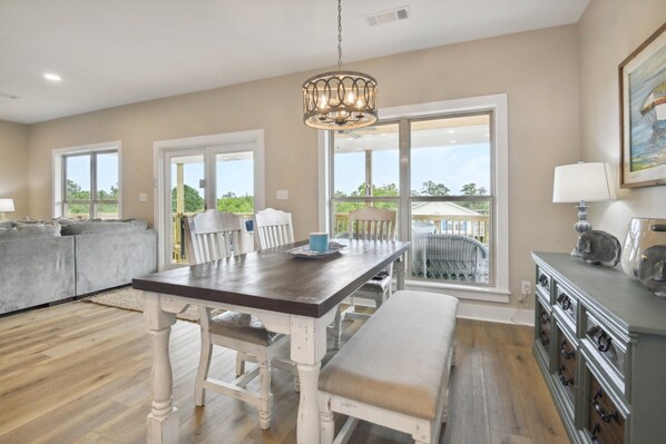 Enjoy a spacious living area with a dining table, sofa, and additional seating near a large window offering a view of the outdoors.