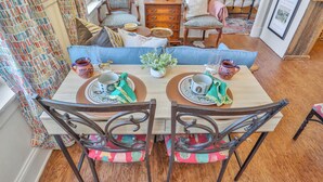 Un comedor con mesa de madera, dos sillas y un sofá azul. Hay una planta pequeña sobre la mesa y un cuadro en la pared.