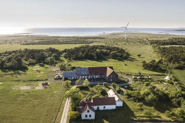 An aerial view of a rural property with a large barn, a smaller white house, and a wind turbine in the distance.