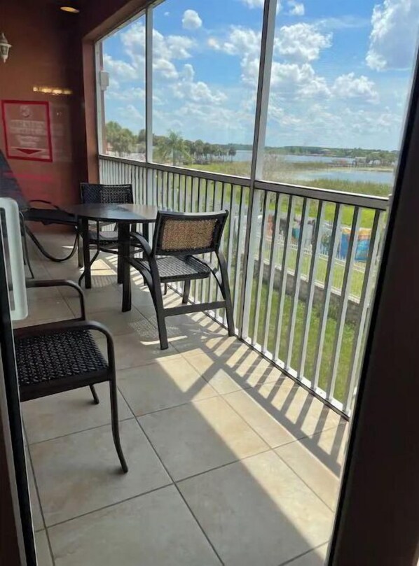 Enjoy the serene views of the water and lush surroundings from this balcony, featuring two tables and four chairs.