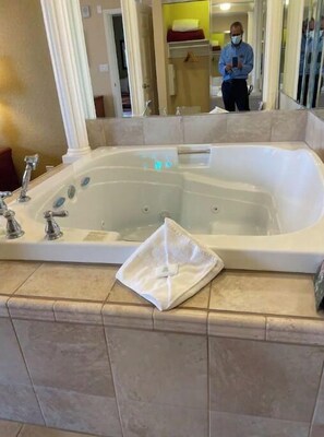 Bathroom features a bathtub, tiled floor, and large mirror.