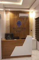 Balcão de recepção com acabamento em madeira, um logotipo com um diamante azul e um aparelho de ar condicionado acima.