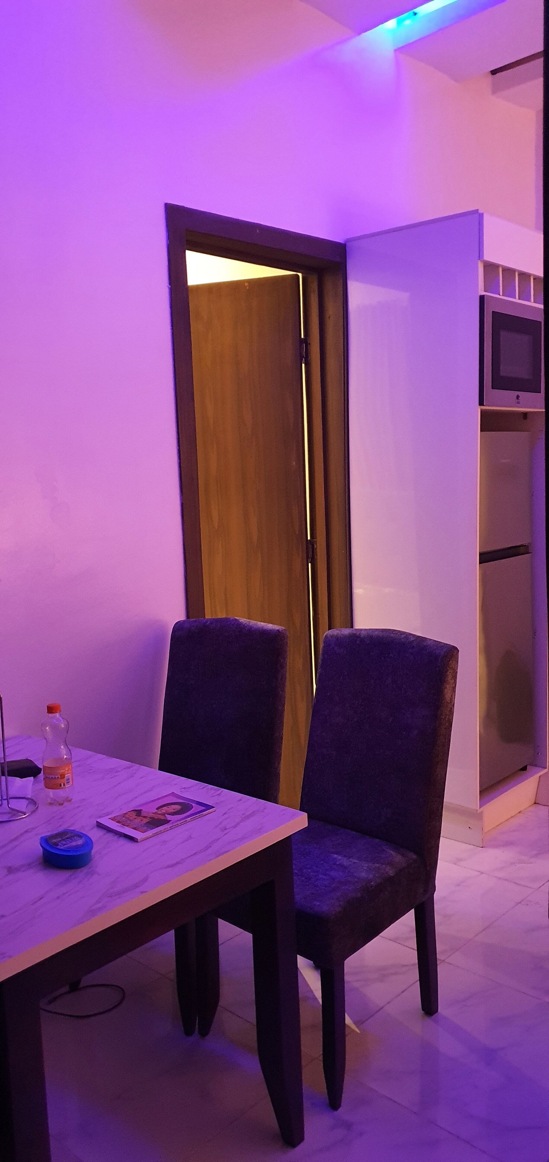A room with a wooden door, a white wall, and a white cabinet with a television.