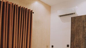 A neatly made bed with white and orange pillows, a tufted headboard, and a wooden wardrobe. - Sapphire Residences by Crystal (Lagos)
