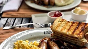 A plate with scrambled eggs, sausages, beans, and grilled toast.
