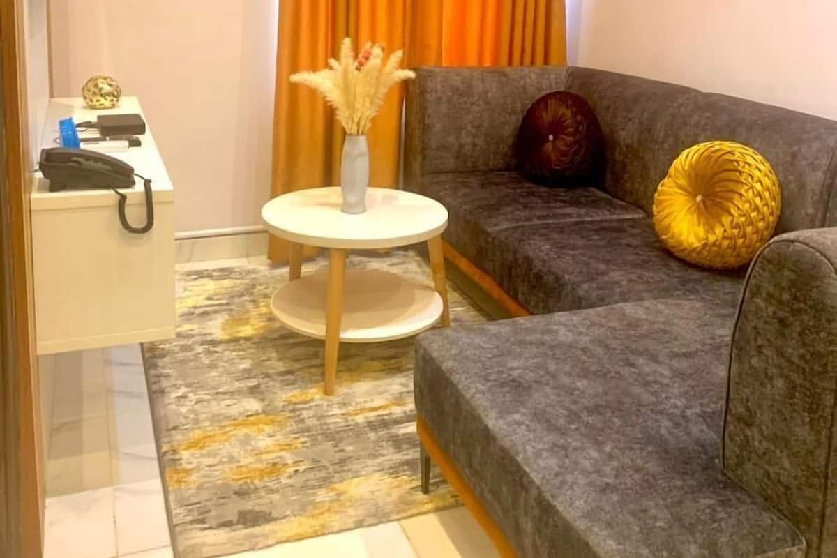 A modern living room with a grey sofa, a small round table with a vase, and a decorative ball on the sofa.