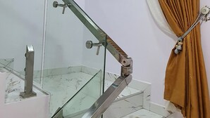 A marble staircase with glass railings, a mirror, and a golden curtain. - Sapphire Residences by Crystal (Lagos)
