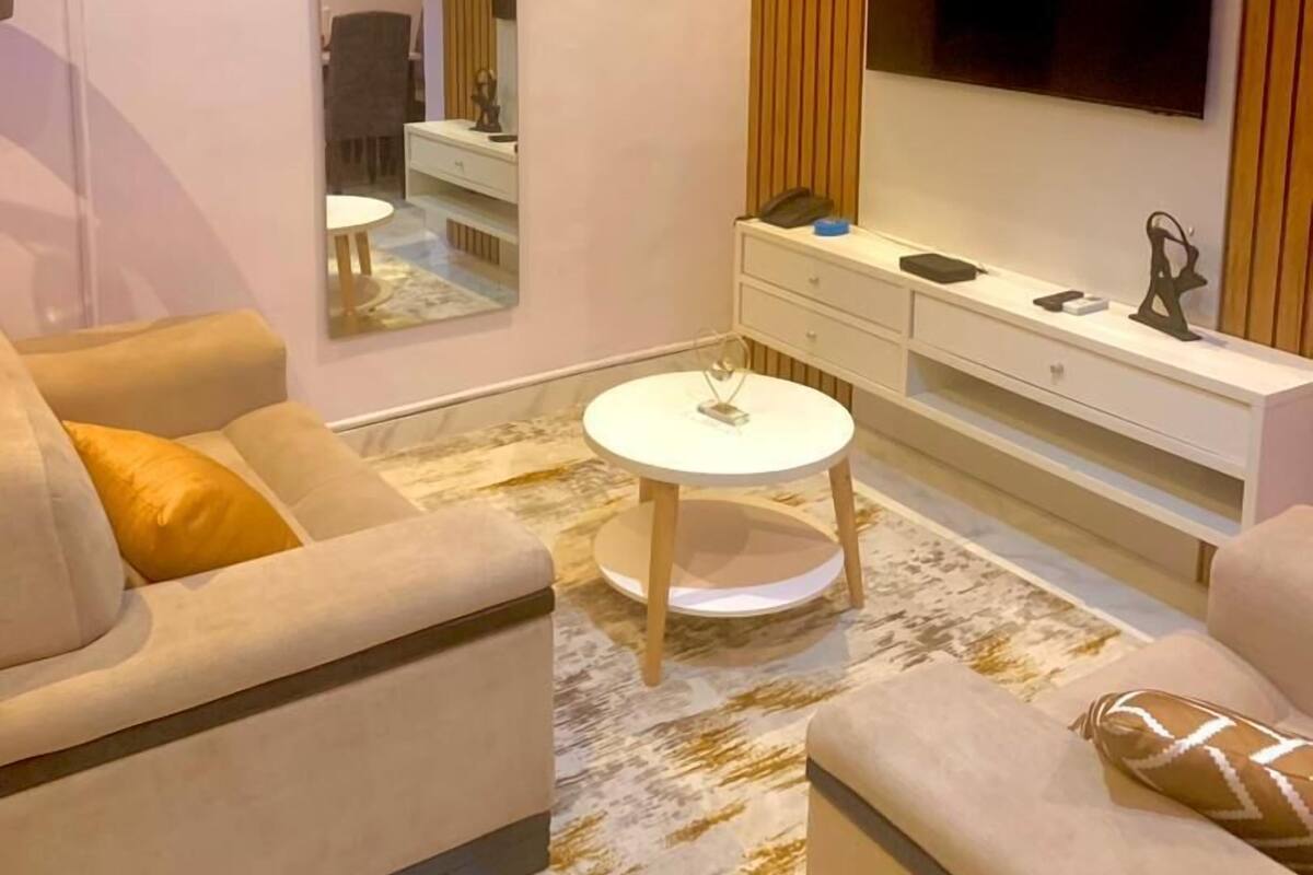 A modern living room with a sofa, a coffee table, a TV, and a mirror.