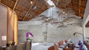 A spacious lobby with a high ceiling, a reception desk, seating area, and a large plant. - The Hava Ubud A Pramana Experience (Ubud)