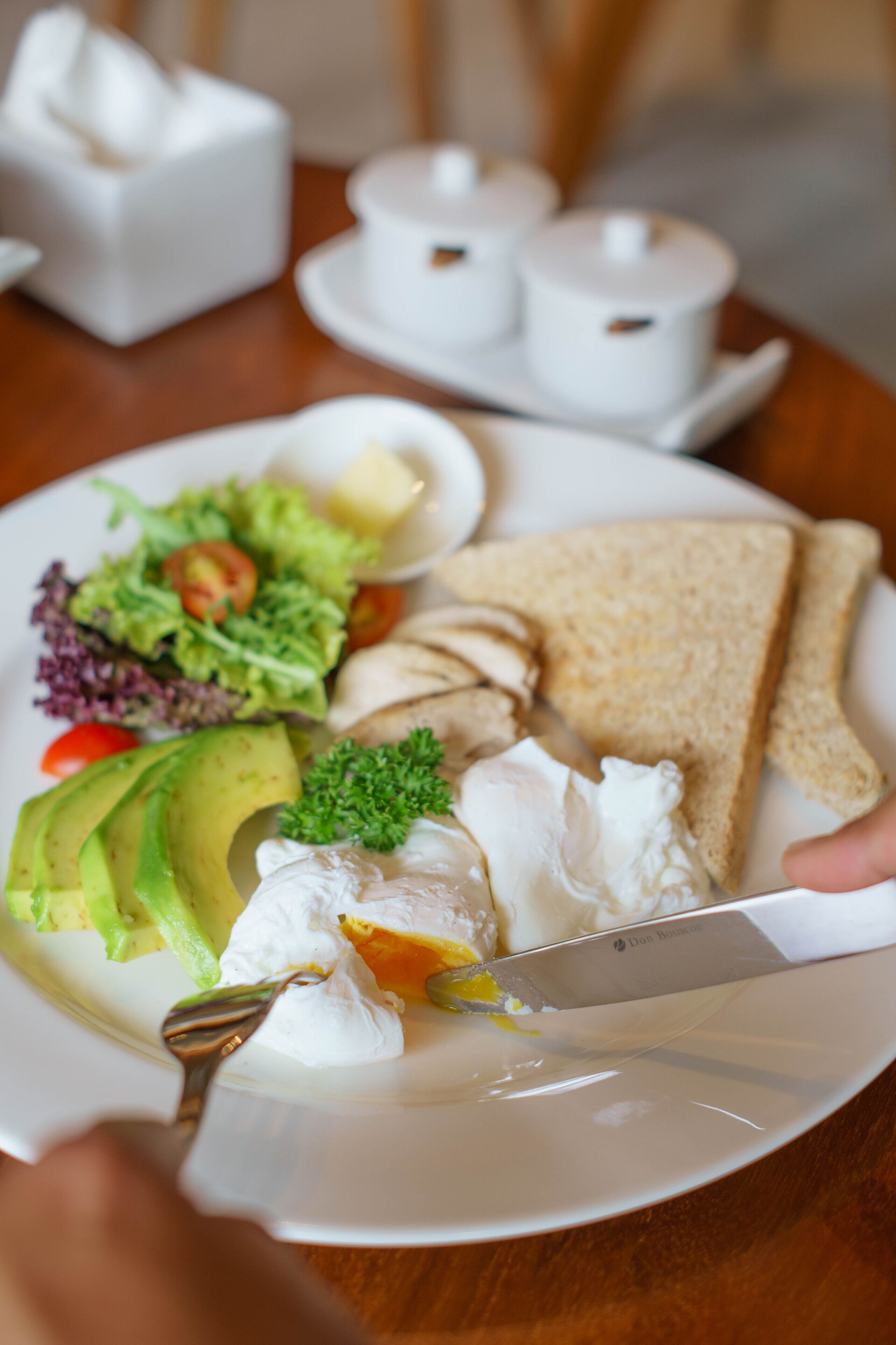 A plate with toast, avocado, salad, and a knife.